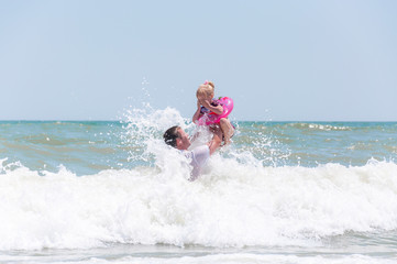 Father and daughter are playing and jumping in the sea foam