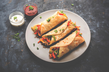 Indian Veg chapati Wrap / Kathi Roll, served in a plate with sauce over moody background. selective focus