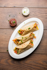 Indian Veg chapati Wrap / Kathi Roll, served in a plate with sauce over moody background. selective focus