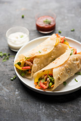 Indian Veg chapati Wrap / Kathi Roll, served in a plate with sauce over moody background. selective focus