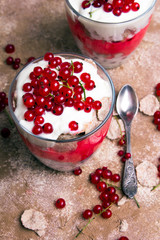 Healthy dessert with organic red currants, fresh yogurt and corn flakes. Dietary breakfast on a brown background