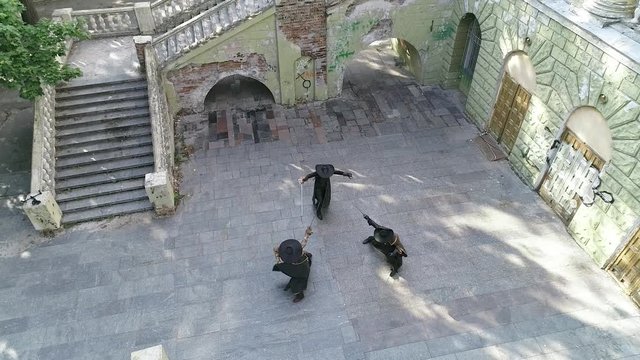 A view from the air, an unequal battle, a musketeer kills one of the opponents and takes off his hat. Slow motion