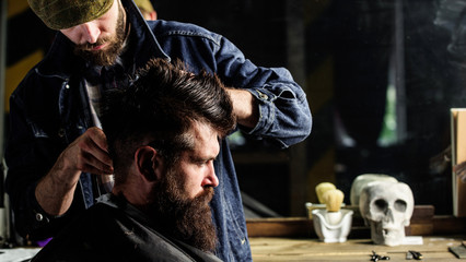 Hipster client getting haircut. Barber styling hair of brutal bearded client with clipper. Barber...