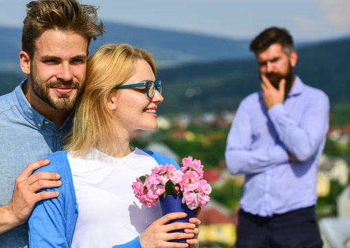 Lovers hugs outdoor flirt romance relations. Couple romantic date lovers bouquet flowers. Couple in love dating while jealous bearded man watching wife cheating him with lover. Infidelity concept
