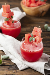 Cold watermelon juice with sage on the wooden table, selective focus