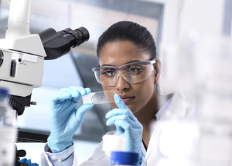 Female scientist examining a human sample on a microscope slide