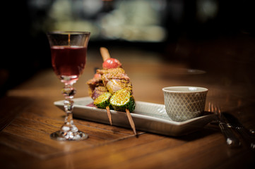 Red cocktail and delicious snack on the plate