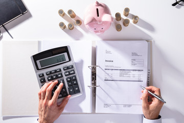 Elevated View Of Businessman Calculating Invoice