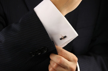 Elegant young fashion man fixing a gold cufflinks