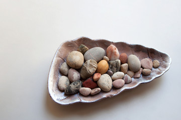 Sea stones with various colors and shapes in seashell isolated on white background