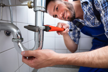 Plumber Repairing Sink In Bathroom