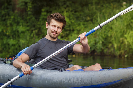 A young man rowing of paddle in kayak. Rafting on the river in a kayak in the summer season. Leisure. The guy in the boat