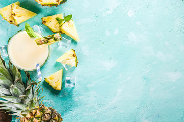 Refreshing summer drink, homemade pina colada cocktail, on a light blue background, with pieces of...