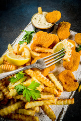 English traditional fast food, junk food, British dish Fish and chips with tartar sauce, lemon and greens, on a dark blue background, copy space above