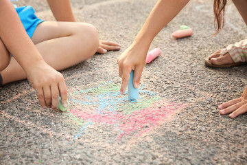 Children drawing with chalk on asphalt, outdoors