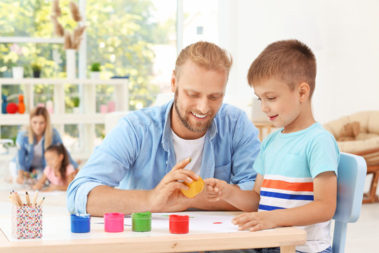 Father painting with cute son at home