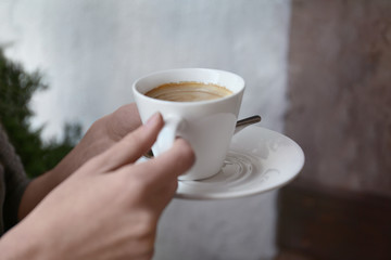 Young woman with cup of delicious coffee on blurred background