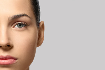 Young woman with natural eyebrows on grey background