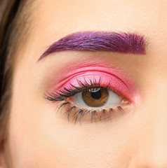 Fototapeta premium Young woman with dyed eyebrow and creative makeup on dark background, closeup