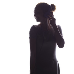 silhouette of romantic a girl listening to music in headphones on a white isolated background