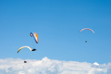 Three paragliders flying in the blue sky against the background of clouds. Paragliding in the sky...