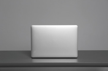 Modern laptop on table against gray background