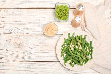 Plate with tasty green beans and almonds on wooden table, top view