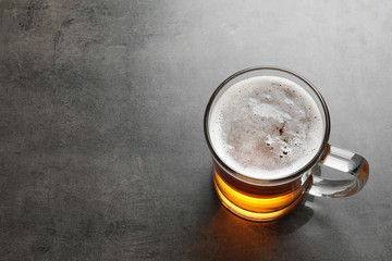Glass mug with cold tasty beer on grunge background, view from above