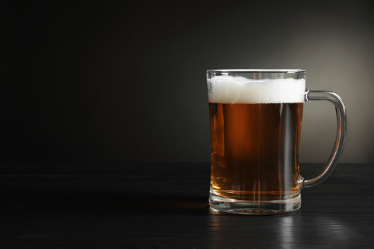 Glass mug with cold tasty beer on dark background