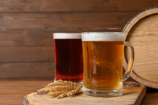 Glass mugs with different types of cold tasty beer on wooden table