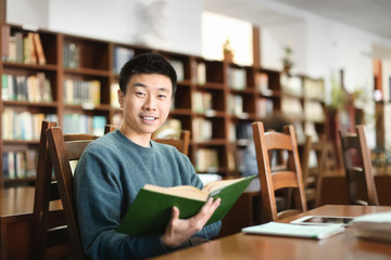 Asian student with book studying in library