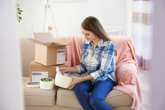 Young woman opening parcel at home