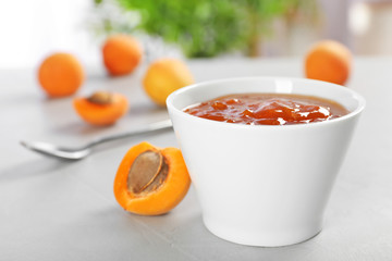 Bowl with tasty apricot jam on table