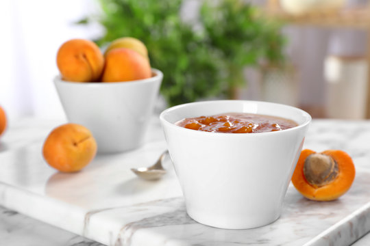 Bowl with tasty apricot jam on table
