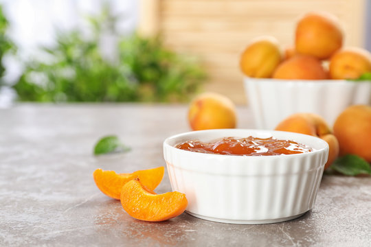 Bowl with tasty apricot jam on table