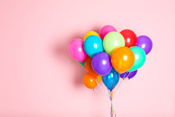 Bunch of bright balloons on color background with space for design
