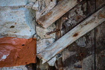 The texture of the destroyed brick and wooden wall with rusty nails