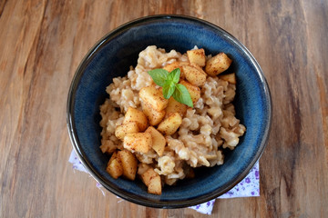 Porridge with apples and cinnamon topped with mint in a blue bowl. British cuisine meal