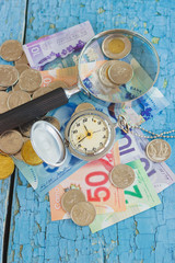 Canadian dollars, pocket clock, magnifying glass and coins on the wooden background