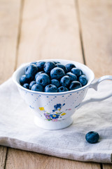 blueberry in a white vintage cup on a wooden table