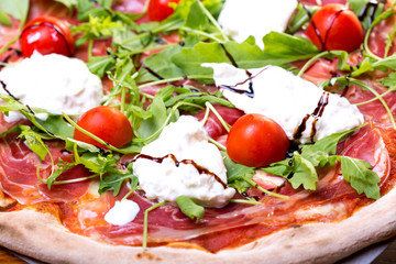 close up of delicious italian pizza with ham, mozzarella and tomatoes
