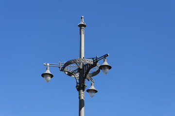 Fototapeta na wymiar Old lamp post with 3 lights against a bright blue sky