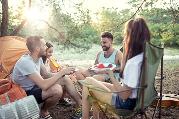 Party, camping of men and women group at forest. They relaxing and eating barbecue