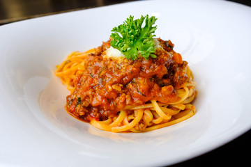 Spaghetti topped with ketchup, minced pork Add fresh tomatoes and sprinkle with parsley. Serve in a white plate.