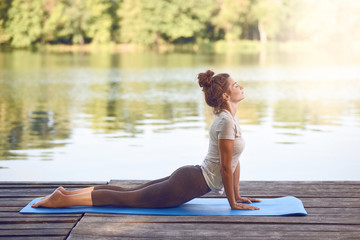 Junge Frau macht eine Yoga Übung am See