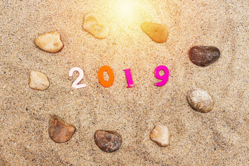 colorful wooden numbers forming the number 2019 on sand and stones all around , For the new year 2019