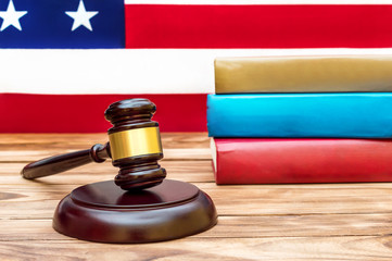 Judge's gavel with stack of books against american flag.