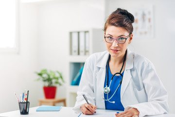 Portrait of Woman Doctor at her Medical Office writing Prescription