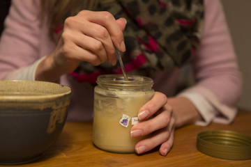 Fototapeta na wymiar Junge Frau löffelt sich Honig aus einem Glas