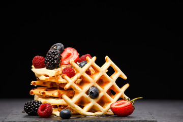 Photo of viennese wafers with berries pouring honey on black background